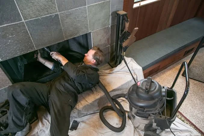 Chimney technician cleaning a fireplace with protective coverings in place