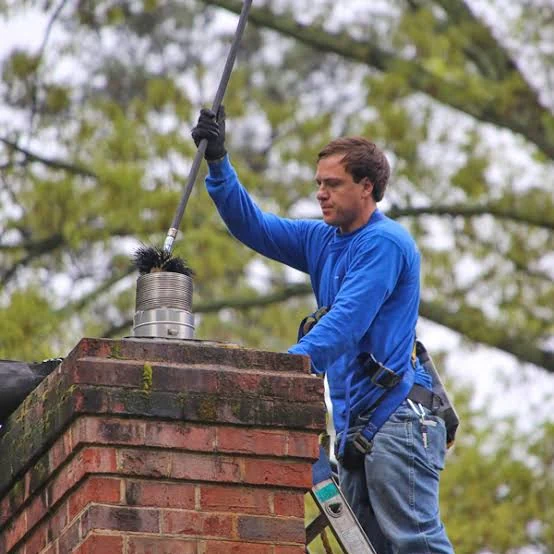 Technician brushing the flue of a residential brick chimney