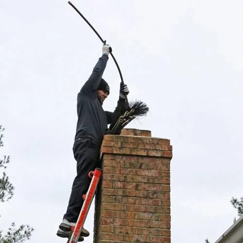 Technician using a sweeping rod at the top of a brick chimney